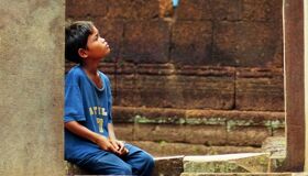 Little Khmer Boy sitting at the temple in Angkor Complex, Siem Reap
